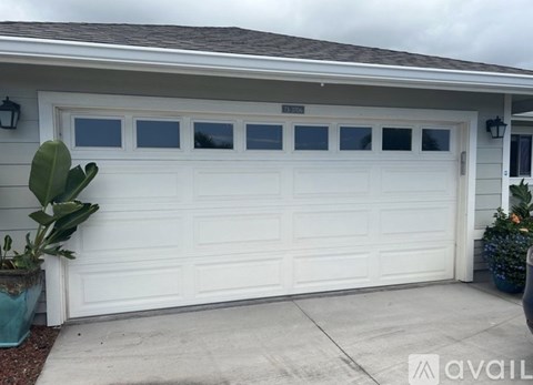 A white garage door with a brown roof and a sign that says "AVAILABLE".