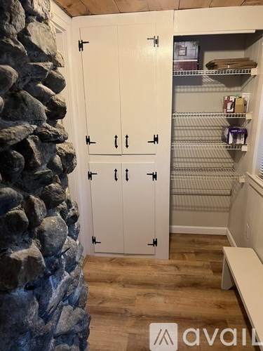 A white double door cabinet with a stone wall on the left side.