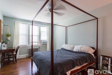 A bedroom with a four poster bed and a window with blinds.