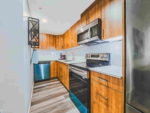 A kitchen with wooden cabinets and a black microwave above the stove.