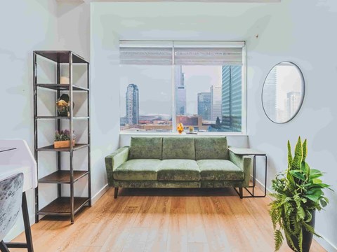 A living room with a green couch and a view of the city.