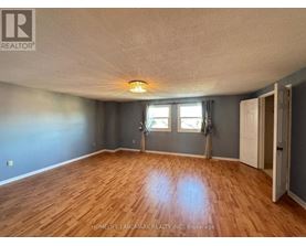 A room with wooden flooring and a window with a view of trees.