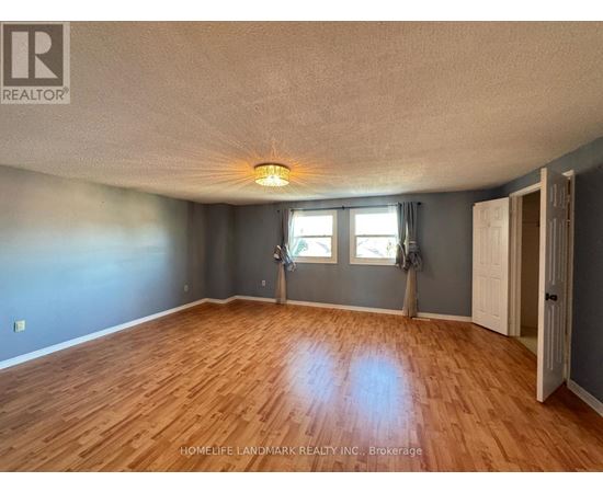 A room with wooden flooring and a window with a view of trees.