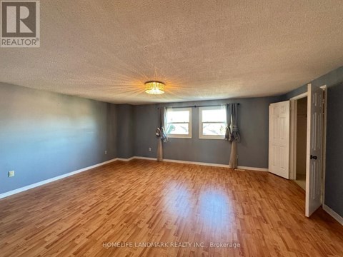 A room with wooden flooring and a window with a view of trees.