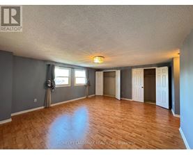 A spacious room with wooden flooring and a large window.