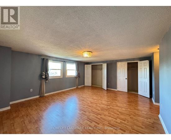 A spacious room with wooden flooring and a large window.