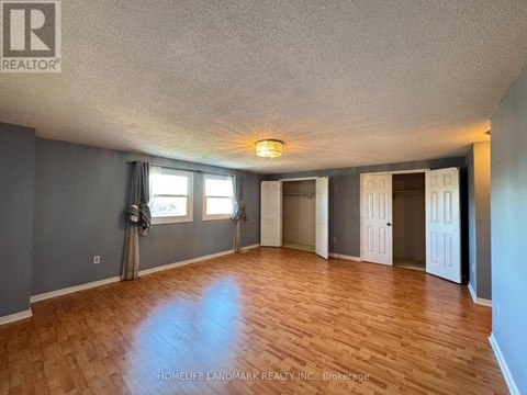 A spacious room with wooden flooring and a large window.