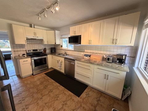 A kitchen with white cabinets and tile backsplash.