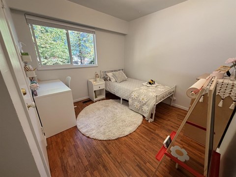 A bedroom with a bed, dresser, and window.