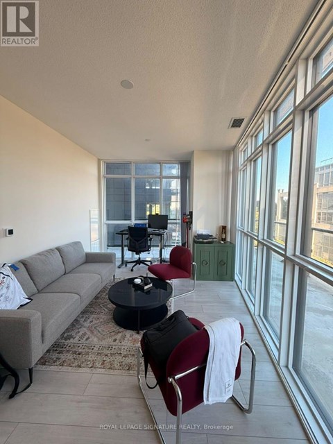 A living room with a grey couch, a black coffee table, and a red chair.