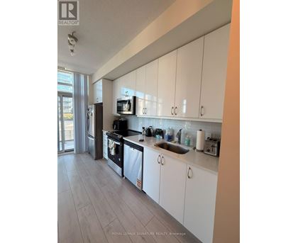 A kitchen with white cabinets and a stainless steel refrigerator.