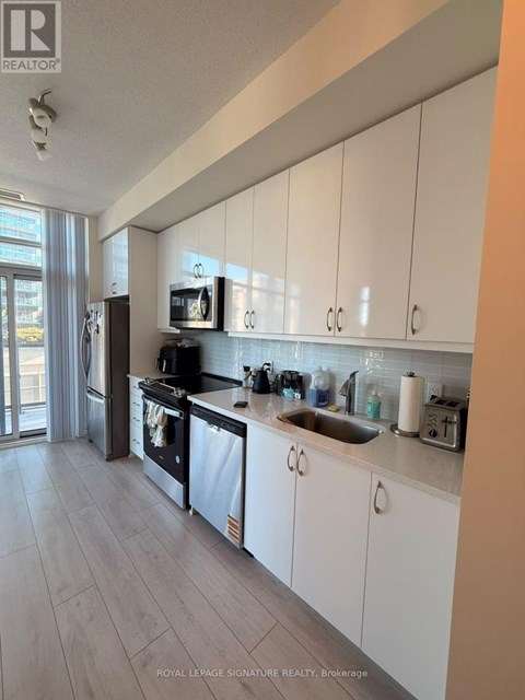 A kitchen with white cabinets and a stainless steel refrigerator.