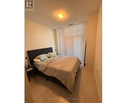 A bedroom with a bed, nightstand, and window with blinds.