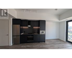 A modern kitchen with black cabinets and stainless steel appliances.