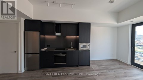 A modern kitchen with black cabinets and stainless steel appliances.