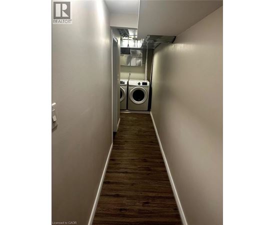 A long hallway with a washer and dryer in the background.