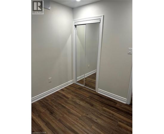 A room with a white door and wood flooring.