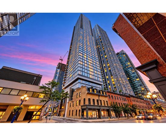 A tall glass building stands in the middle of a city street.