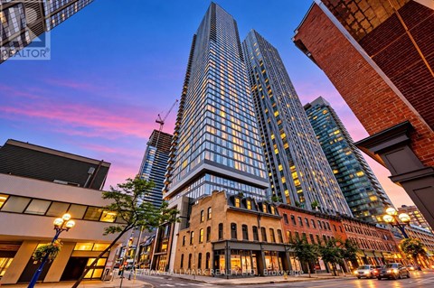 A tall glass building stands in the middle of a city street.