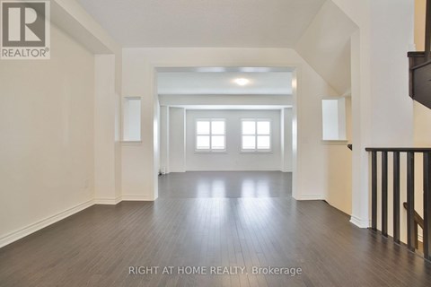 A spacious room with wooden floors and white walls.