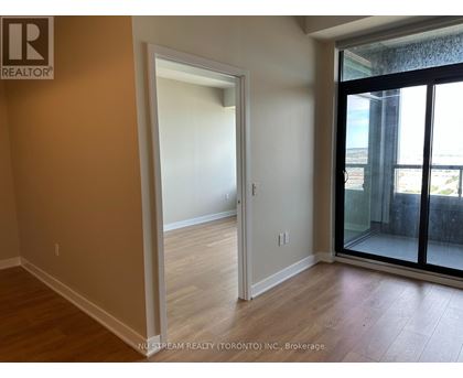 A room with a doorway leading to another room and a balcony with a glass door.