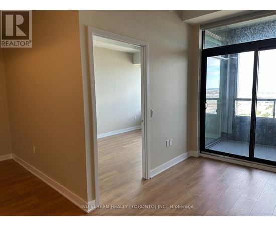 A room with a doorway leading to another room and a balcony with a glass door.