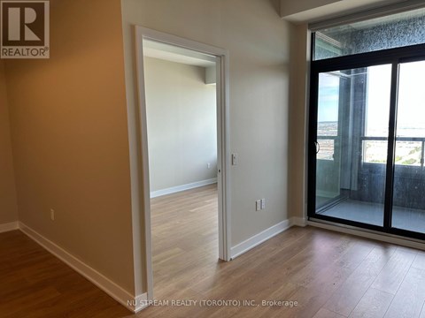 A room with a doorway leading to another room and a balcony with a glass door.