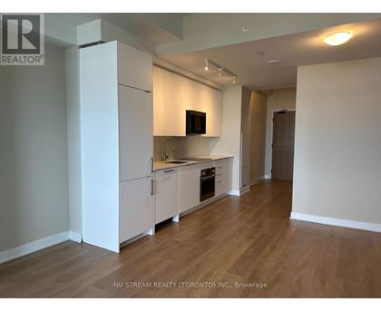 A kitchen with white cabinets and a wooden floor.