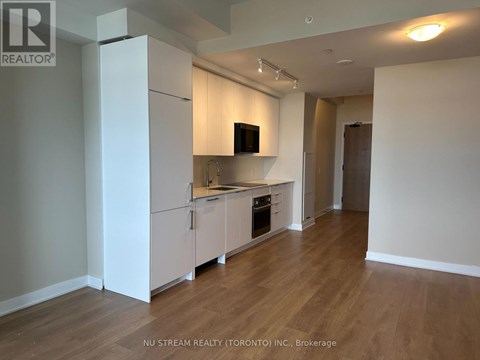 A kitchen with white cabinets and a wooden floor.