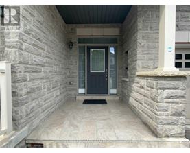A stone house entrance with a black door and a doormat.
