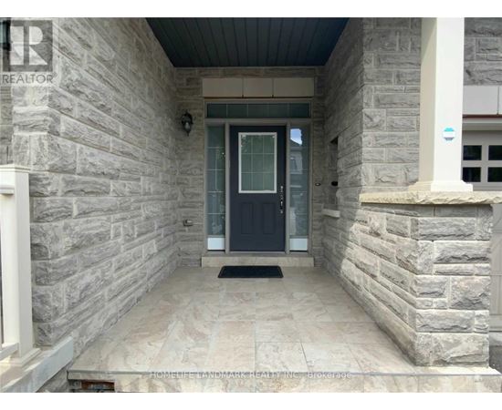 A stone house entrance with a black door and a doormat.