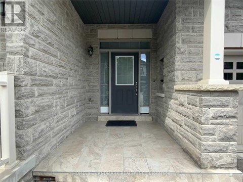 A stone house entrance with a black door and a doormat.