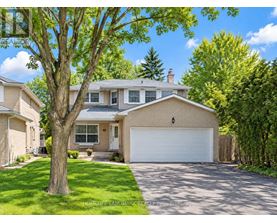 A large house with a driveway and a tree in front.