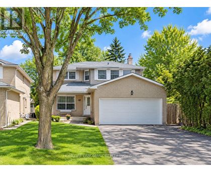 A large house with a driveway and a tree in front.
