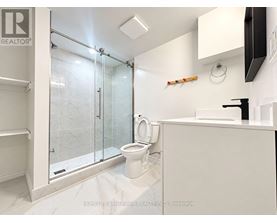 A white bathroom with a glass shower door and a toilet.