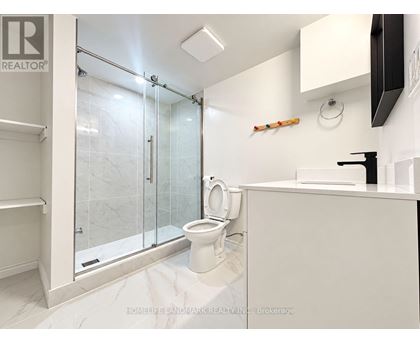 A white bathroom with a glass shower door and a toilet.