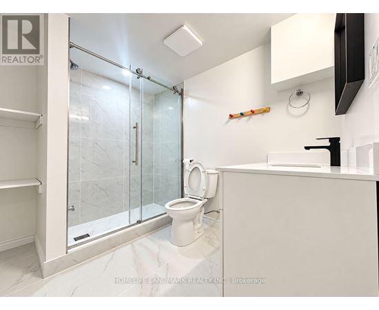 A white bathroom with a glass shower door and a toilet.