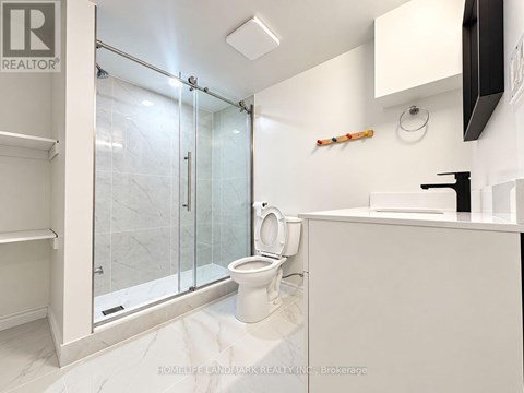 A white bathroom with a glass shower door and a toilet.