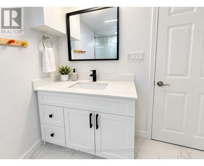 A white bathroom vanity with a black mirror above it.