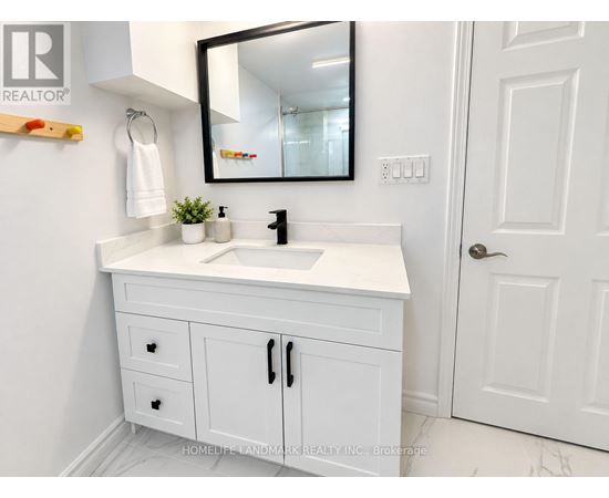 A white bathroom vanity with a black mirror above it.