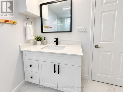 A white bathroom vanity with a black mirror above it.