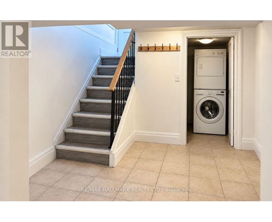 A hallway with a staircase and a washing machine in the doorway.