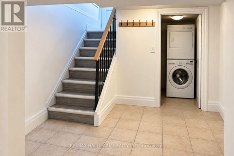 A hallway with a staircase and a washing machine in the doorway.
