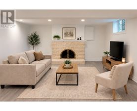 A living room with a couch, a chair, and a fireplace.
