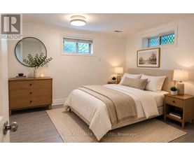 A bedroom with a bed, nightstand, and a round mirror on the wall.