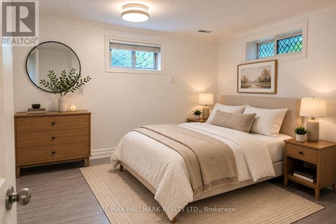 A bedroom with a bed, nightstand, and a round mirror on the wall.
