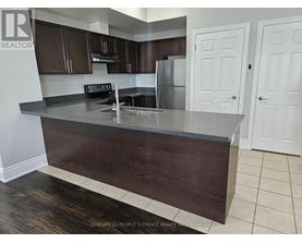 A kitchen with dark wood cabinets and a stainless steel refrigerator.