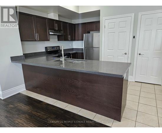 A kitchen with dark wood cabinets and a stainless steel refrigerator.