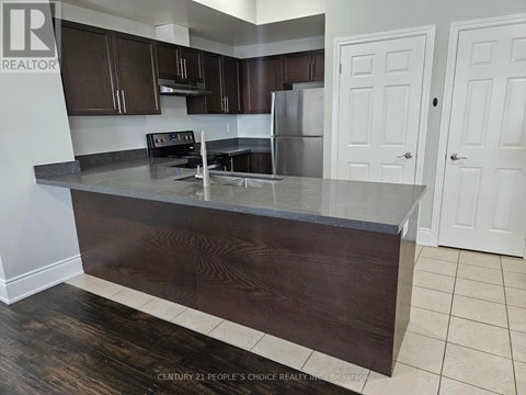 A kitchen with dark wood cabinets and a stainless steel refrigerator.