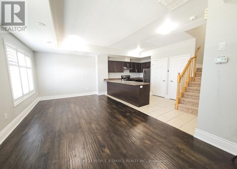 A spacious room with wooden floors and a staircase leading to another room.